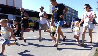 Dzieci biegnące ulicą w towarzystwie dorosłych podczas biegu dla dzieci Drzewica Kids Run na Osiedlu Bolesława Chrobrego.
