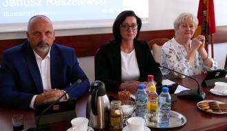 Prezydium Rady Miejskiej w Drzewicy. Przy stole prezydialnym siedzą od lewej: Wiceprzewodniczący Paweł Małek, Przewodnicząca Dorota Wiktorowicz, Wiceprzewodnicząca Joanna Popis. Przed nimi znajdują się mikrofony, tablety z herbem Drzewicy, napoje oraz filiżanki.