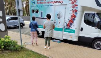 Dwie kobiety stoją przed białym osteobusem z napisem „Densytometria badanie osteoporozy”.