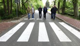 Sześciu uczestników odbioru idzie przebudowaną drogą przed przejściem dla pieszych na ulicy Słowackiego w Drzewicy