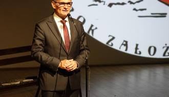 Burmistrz Drzewicy Janusz Reszelewski przemawia na scenie sali widowiskowej RCK. W tle część loga Towarzystwa Przyjaciół Drzewicy