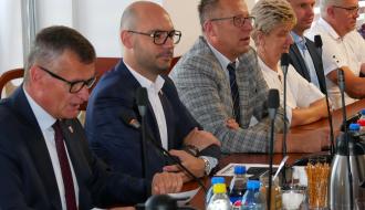 Siedząc głos zabiera Burmistrz Drzewicy Janusz Reszelewski. Po prawej siedzą: Zastępca Burmistrza Dominik Niemirski oraz radni (cztery osoby). 