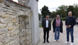 Przy zabytkowej bramie cmentarnej z odkrytym przejściem we wschodniej ścianie stoją od lewej: Burmistrz Drzewicy Janusz Reszelewski, Jarosław Bomba – Kierownik Referatu Gospodarki Komunalnej, Budownictwa i Inwestycji Urzędu Miejskiego w Drzewicy oraz Zastępca Burmistrza Drzewicy Dominik Niemirski. 