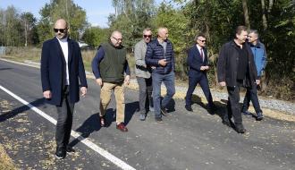 Wyremontowaną drogą w Brzustowcu – Starej Wsi idą uczestnicy odbioru – siedmiu mężczyzn