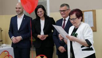 Z uśmiechem na twarzy stoją od lewej: Zastępca Burmistrza Drzewicy Dominik Niemirski, Przewodnicząca Rady Miejskiej w Drzewicy Dorota Wiktorowicz, Burmistrz Drzewicy Janusz Reszelewski oraz Przewodnicząca Nauczycieli Emerytów i Rencistów Gminy Drzewica Maria Staniszewska, która trzyma w rękach kartkę z listą gości.