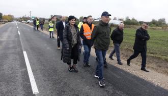 Uczestnicy odbioru – kilkanaście osób - idą przebudowaną drogą powiatową między Krzczonowem a Jelnią