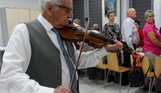 Pan Stanisław Wolski – najstarszy mieszkaniec Gminy Drzewica – gra na skrzypcach. W tle stoją inni emeryci