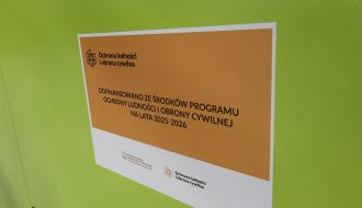 Tabliczka na zielonym agregacie prądotwórczym, informująca o dofinansowaniu z Programu OLiOC.