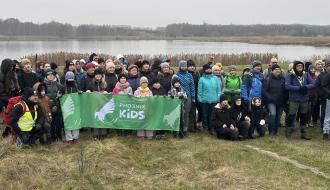  Na tle Zalewu Drzewickiego kilkudziesięcioosobowa grupa uczestników rajdu pieszego „Andrzejkowy Survival” wraz z młodzieżą trzymającą baner Pho3nix Kids