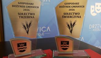 Dwie szklane statuetki z napisem „Gospodarz Dożynek Gminnych 2026” i herbem Drzewicy – na jednej napis „Sołectwo Trzebina”, na drugiej „Sołectwo Świerczyna”.