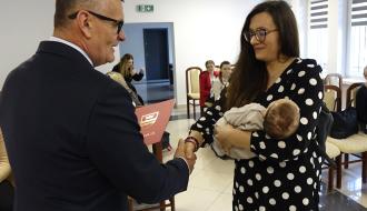 Burmistrz Drzewicy Janusz Reszelewski przekazuje gratulacje mamie trzymającej małe dziecko