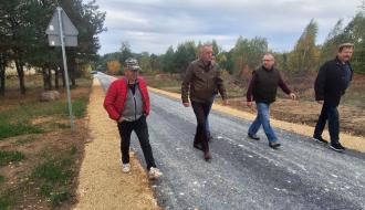 Czterej mężczyźni idą nowym odcinkiem drogi asfaltowej w Brzustowcu-Smugach podczas odbioru inwestycji. 