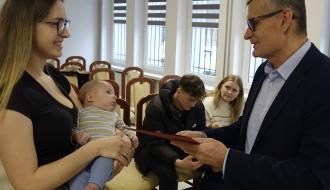 Burmistrz Drzewicy Janusz Reszelewski przekazuje gratulacje mamie trzymającej małe dziecko