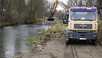 Pierwsze prace z użyciem ciężkiego sprzętu. Po lewej rzeka, po prawej ciężarówka a za nią ramię koparki