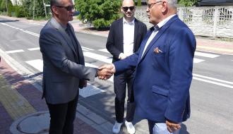 Uściski dłoni podczas oficjalnego spotkania na chodniku. I Wicewojewoda Łódzki w niebieskiej marynarce (po prawej) i Burmistrz Drzewicy w szarym garniturze, obok stoi Wiceburmistrz Drzewicy w czarnej marynarce.