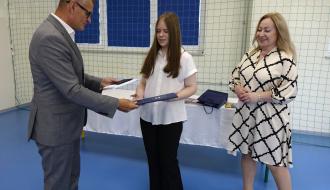 Wręczenie dyplomu uczennicy przez Burmistrza Drzewicy w sali gimnastycznej w obecności Pani Dyrektor SP w Idzikowicach.