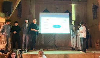 Siedmioro uczestników projektu stoi na scenie wokół ekranu
