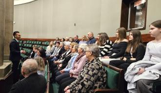 Drzewicka grupa siedzi na galerii Sali Posiedzeń Sejmu RP. Przed słuchaczami Poseł Adrian Witczak