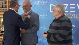 Burmistrz Drzewicy Janusz Reszelewski przypina I Wicewojewodzie Łódzkiemu Markowi Mazurowi odznakę z okazji 100-lecia klubu sportowego w Drzewicy. Obok Prezes MGKS Drzewica Andrzej Sosnowiec