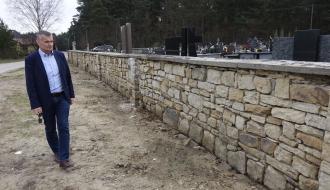 Burmistrz Drzewicy Janusz Reszelewski ogląda północny, oczyszczony odcinek muru cmentarnego