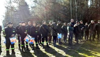 Kilkudziesięcioosobowa grupa drzewicka podczas zbiórki rozpoczynającej poszukiwania na polanie przy lesie