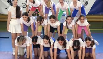 Kilkunastoosobowa grupa uczennic w trzypoziomowym układzie gimnastycznym