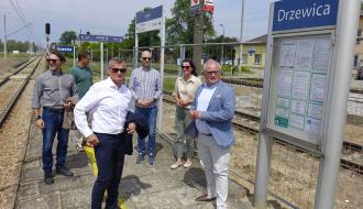 Uczestnicy odbioru (sześć osób) stoją przy tablicy informacyjnej na peronie stacji PKP Drzewica