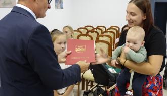 Burmistrz Drzewica Janusz Reszelewski wręcza list gratulacyjny trzymającej dziecko mamie