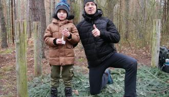 W lesie na terenie Domku Myśliwskiego Antek Krzyżanowski z pucharem dla najmłodszego piechura i klęczący na jednym kolanie Prezes LGD Waldemar Pęczkowski.