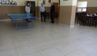 Główne pomieszczenie świetlicy z nowymi płytkami podłogowymi. W tle stoi trzech uczestników odbioru.