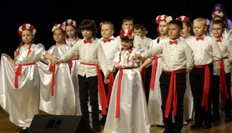 Na scenie poloneza tańczy kilkunastoosobowa grupa uczniów SP w Radzicach Dużych ubrana w biało-czerwone stroje