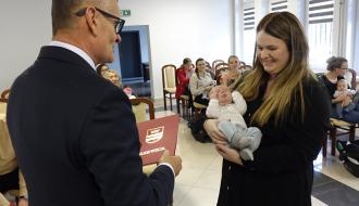 Burmistrz Drzewicy Janusz Reszelewski przekazuje gratulacje mamie trzymającej małe dziecko