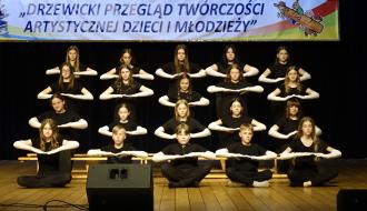 Na scenie dwudziestoosobowa grupa uczniów SP w Drzewicy ( w czterech rzędach) prezentuje układ synchroniczny do muzyki