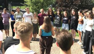 Kilkunastoosobowa grupa uczestników projektu podczas warsztatów edukacyjnych na placu przy budynku ośrodka wypoczynkowego