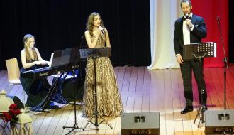 Na scenie widowiskowej RCK występuje troje artystów: pianistka oraz dwoje śpiewaków. Panie ubrane są w długie suknie, mężczyzna w garnitur