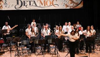 Młodzieżowa Orkiestra Dęta z Drzewicy na scenie RCK podczas Festiwalu Orkiestr Dętych „DĘTA MOC Drzewica 2026”. Kapelmistrzyni kłania się widowni, kładąc dłoń na sercu.