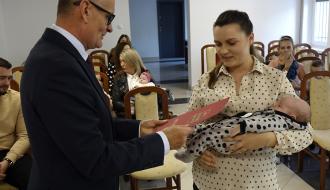 Burmistrz Drzewicy Janusz Reszelewski przekazuje gratulacje mamie trzymającej małe dziecko