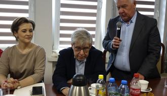 Od lewej siedzą: Dyrektor SP w Brzustowcu Barbara Stolarczyk oraz Piotr Ciesielski. Po prawej stoi, zabierając głos do mikrofonu, Jerzy Ciesielski. Panowie Piotr i Jerzy to wnukowie patrona szkoły z Brzustowca, Jana Szymańskiego