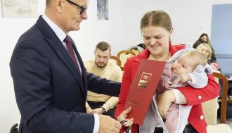 Burmistrz Drzewicy Janusz Reszelewski przekazuje gratulacje mamie trzymającej małe dziecko