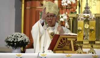 Arcybiskup Wacław Depo w mitrze, stojąc przy ołtarzu nakrytym obrusem z haftem maryjnym, wykonuje gest błogosławieństwa prawą ręką, trzymając pastorał w lewej dłoni.