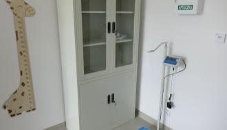 Wyposażony gabinet z wagą, szafą na materiały medyczne, apteczką oraz miarką wzrostu dla dzieci.