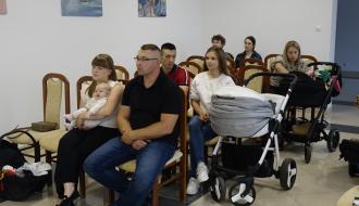 Widok ogólny na salę USC. Rodzice z bobasami siedzą na krzesłach. 