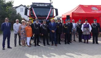 Uczestnicy uroczystości na tle przekazanego samochodu pożarniczego