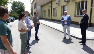 Uczestnicy odbioru (sześć osób) stoją na przebudowanej drodze przy budynku byłego dworca PKP w Drzewicy