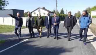 Wyremontowaną drogą w Brzustowcu – Starej Wsi idą uczestnicy odbioru – siedmiu mężczyzn
