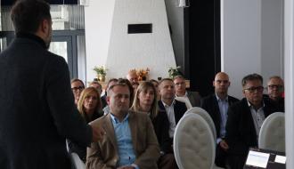 Prelegent prowadzi spotkanie przed grupą osób siedzących na sali konferencyjnej
