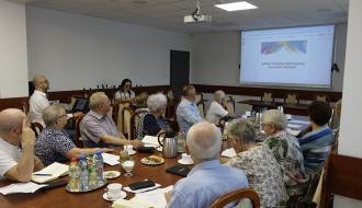 Radni Miejskiej Rady Seniorów w Drzewicy zgromadzeni w sali konferencyjnej Urzędu Miejskiego w Drzewicy podczas komisji wspólnej. Na ekranie prezentacja dotycząca projektu Gminnego programu Rewitalizacji dla Gminy Drzewica. Temat referuje Zastępca Burmistrza Drzewicy Dominik Niemirski