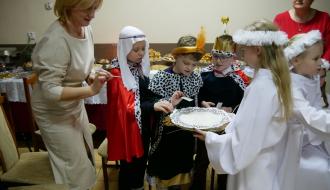 Uczestnicy spotkania łamią się opłatkiem