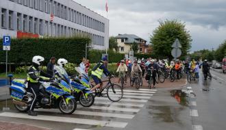 Rozpoczęcie rajdu rowerowego. Na czele dwóch zmotoryzowanych policjantów oraz Zastępca Burmistrza Drzewicy Dominik Niemirski. W tle uczestnicy rajdu na rowerach