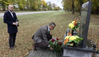 Burmistrz Drzewicy składa wieniec pod pomnikiem, po lewej Zastępca Burmistrza Drzewicy trzyma w dłoni znicz.